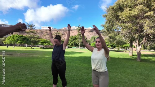 Women warming up before a workout with their instructor in a park