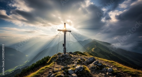 A christian crucifix cross on top of a mountain peak with dramatic sunset sun rays and clouds mountain religion christian crucifix