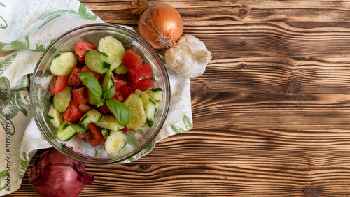 Fresh vegetable salad ingredients and finished dish on rustic wooden table
