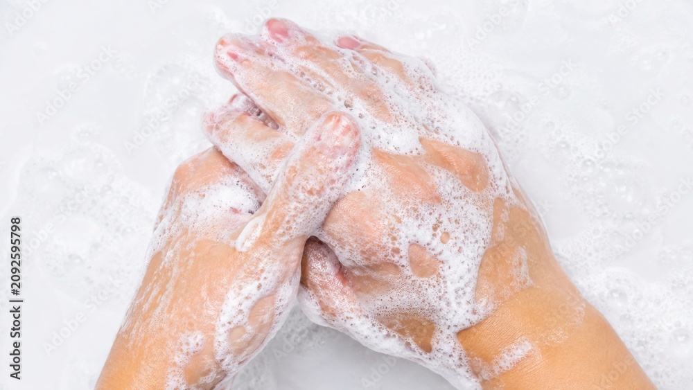 Fototapeta premium Person washing hands with thick white soap foam