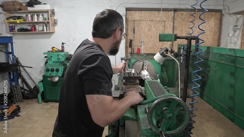 A male lathe operator works at a lathe in a production workshop. Production of metal products.