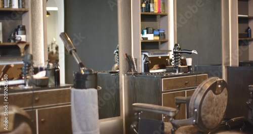 Camera is panning right and zooming in, showing barber chair, counter set for clients in salon
