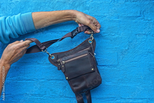 Foto A man holds a handmade brown leather waist bag with an adjustable textile strap, metal snaps and several zippered pockets