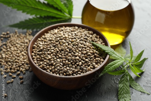Canvastavla Hemp oil, seeds and leaves on black table, closeup