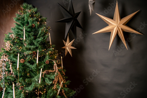 christmas star decoration, black and golden christmas stars and christmas tree as indoor decoration with negative space