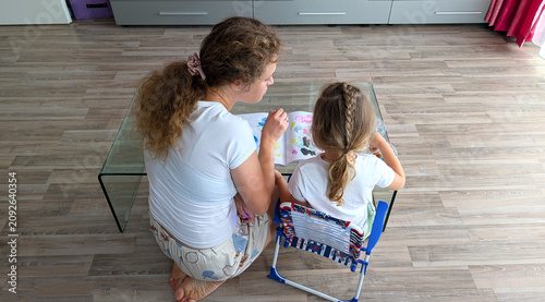 Back View Of Mother And Little Daughter Painting With Watercolors In Sketchbook At Home