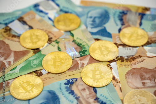 Close up of Bitcoin coins on Canadian dollar banknotes.
