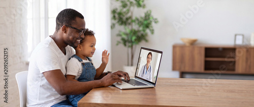 Telehealth family consultation with pediatrician online on a laptop screen with a smiling black father and toddler son waving at the doctor from home for medical advice