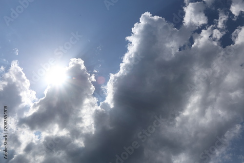 Abstract sky background with fluffy clouds and bright sunlight. The scene captures a serene atmosphere with a blend of blue and white hues.