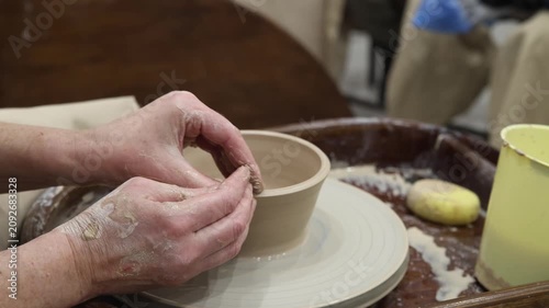 Skilled hands shaping raw clay pot on spinning pottery wheel in ceramic workshop studio, creative handmade craft, art therapy, relaxation hobby, educational modeling activity.