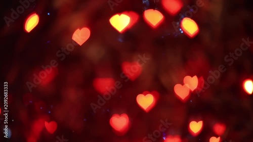 Warm glowing red orange heart shaped bokeh light spots on dark night background creating romantic festive atmosphere for Valentines Day love celebration and holiday greeting card design.