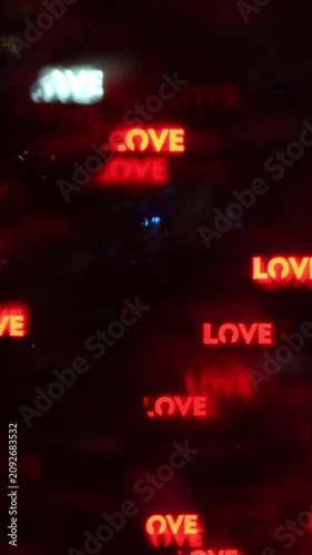 Abstract out of focus glowing red orange LOVE text bokeh light spots on dark blurry night background creating romantic festive atmosphere for Valentine's Day celebration and greeting card design