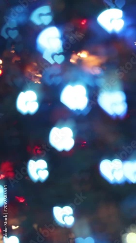 Glowing blue heart shaped bokeh light spots on dark night background creating dreamy romantic festive atmosphere for winter holiday celebration and abstract design.