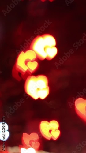 Glowing heart shaped bokeh light spots in warm yellow orange hues on dark abstract background creating romantic festive atmosphere for Valentine's Day love celebration.