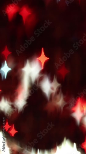 Abstract glowing red and white star-shaped bokeh light spots on a dark night background creating a festive holiday magic atmosphere for beautiful abstract design and decoration.