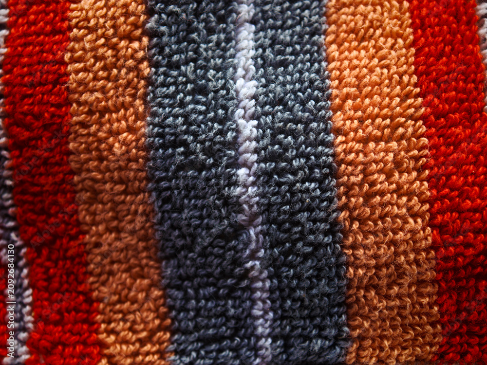 Fototapeta premium Looping textured fabric showing vibrant red, orange, grey, and white stripes creating a tactile and detailed surface