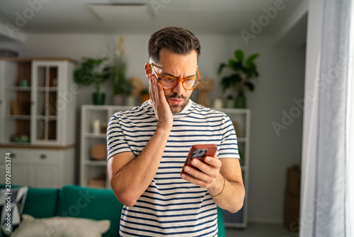 Fotografía Man feeling worried seeing shocking news on smartphone at home
