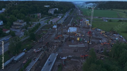 High altitude drone view of railway repair project surrounded by forests meadows and open countryside with distant horizon