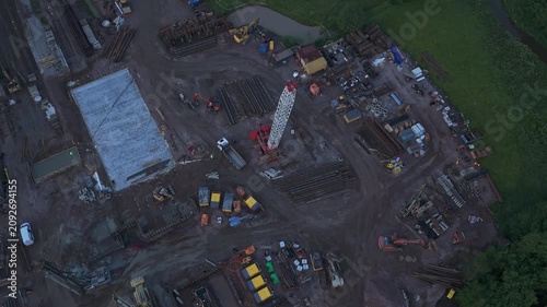 Aerial drone view of active construction site with tower cranes excavators and concrete foundations during early stage of urban development