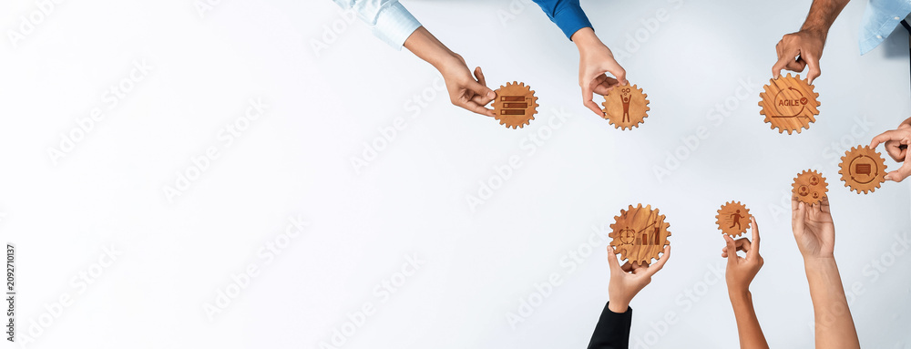 Fototapeta premium Diverse hands interact with wooden gears on a white surface, showcasing the essence of collaboration and strategy in business. Perfect for themes of teamwork and innovation. Amity