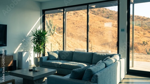 Modern living room with large windows overlooking a desert landscape with cacti and mountains