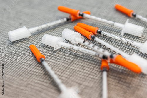 Insulin syringes with orange caps on woven surface