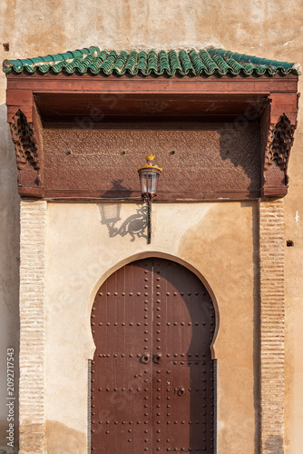Foto Rustic Wooden Door with an Overhang and Lantern at Bab Stinia, Meknes, Morocco