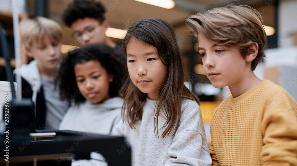 Obraz premium Diverse group of young students observing a 3D printer in action during a technology class, STEM education concept, with copy space