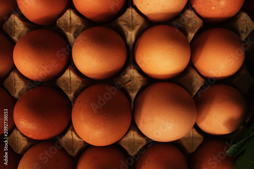 Close up of fresh brown chicken eggs in a cardboard carton tray. Top view background of organic raw eggs.
