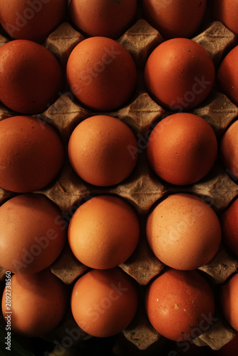Close up of fresh brown chicken eggs in a cardboard carton tray. Top view background of organic raw eggs.