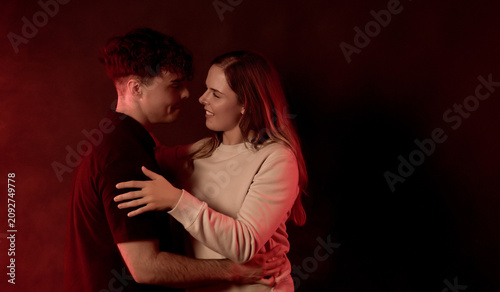 Canvastavla Young couple embracing affectionately under moody red lighting, symbolizing love