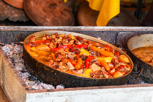 Coked vegetable and meat stew meal inside metal pot sold on local fair