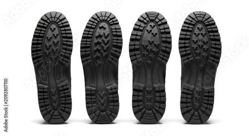 Four black rubber shoe soles on white background.