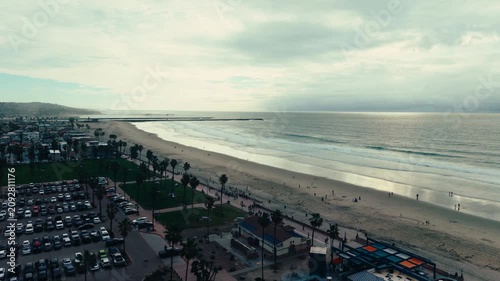 Wide aerial drone view of California beach with ocean waves shoreline and cloudy coastal sky above Pacific coastline