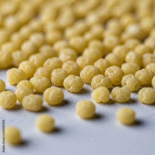 Close up of scattered yellow mustard seeds on white background.