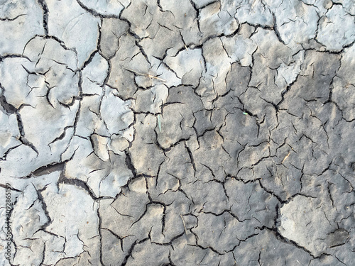 The surface of the earth was cracked by drought, cracks and erosion in the soil. Brown dry soil or cracked ground texture background. clay soil texture after water dry out and arid.

