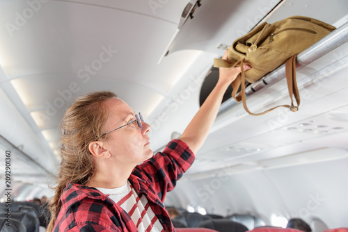 Female passenger is putting her hand luggage in overhead locker