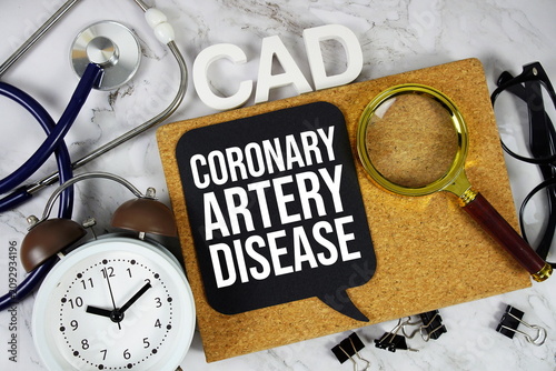 CAD - Coronary Artery Disease acronym with stethoscope, alarm clock and magnifying glass, medical and healthcare concept background