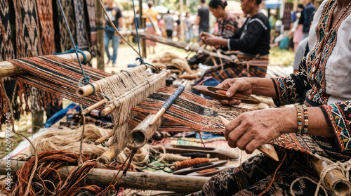 Woman weaving traditional fabric on a loom with intricate patterns.