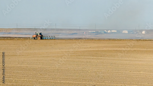 Photography Modern tractor plowing the field for cultivation in the vast agricultural landscape of Xinjiang, China