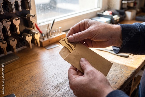 Locksmith packaging brass keys in paper sleeve