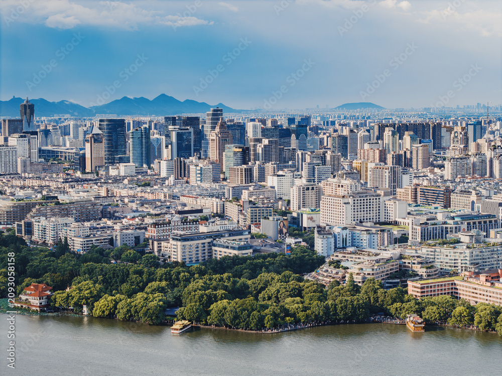 Fototapeta premium Aerial shot of Hangzhou city, West Lake and surrounding mountains framed under white clouds