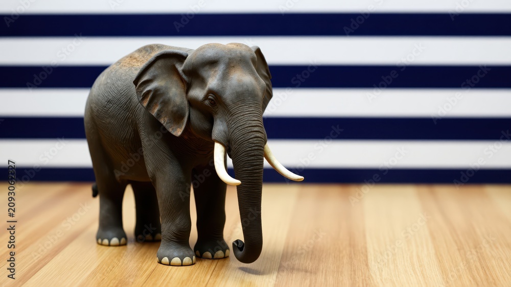Fototapeta premium Majestic Elephant Figurine: A detailed elephant figurine, showcasing its grand tusks and textured skin, stands proudly on a polished wooden surface against a backdrop of bold blue and white stripes.