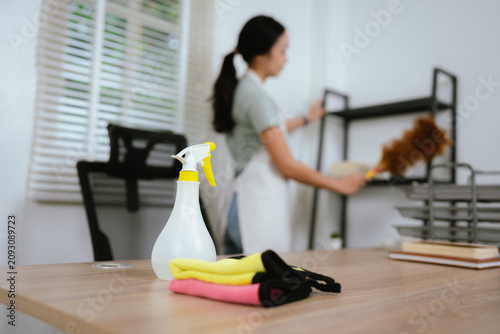 фотографія Young woman cleaning an office desk with disinfectant spray and microfiber cloth in a modern workspace for a hygienic environment