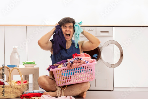 Portrait of frustrated young man screaming while doing laundry