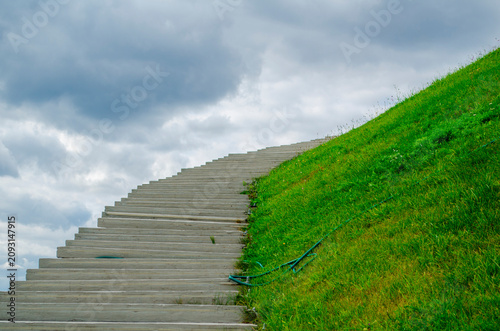 Foto Steps lead up a grassy hill under a cloudy sky in a public area during the dayti