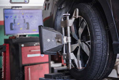 Cuadro en lienzo Wheel alignment target on a car tire with a diagnostic computer screen in the background