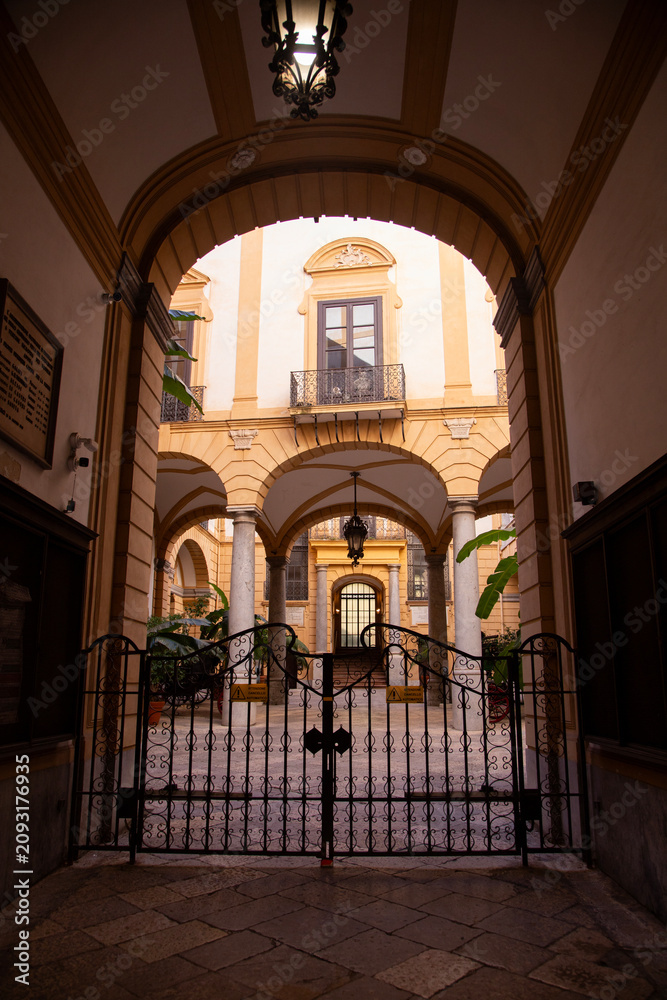 Obraz premium Palermo, Italy; 1st January 2026: Palazzo Comitini courtyard with arches and antique carriages in Palermo.