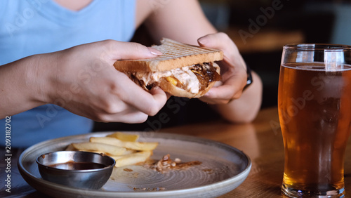 Konstfotografi woman eating sandwich in dark setting with contentment close-up hand bread filling food lifestyle blue brown commercial natural light clean copy space editorial educational visual story web
