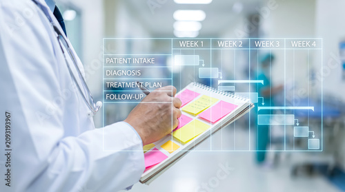 Doctor writing on a notepad with a digital medical project management timeline overlay in a hospital hallway